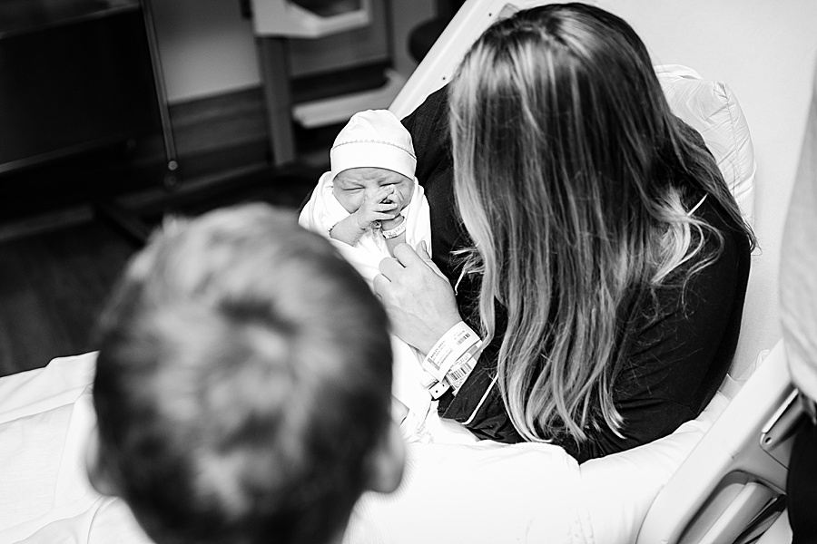 black and white image of newborn with mom and brother looking on