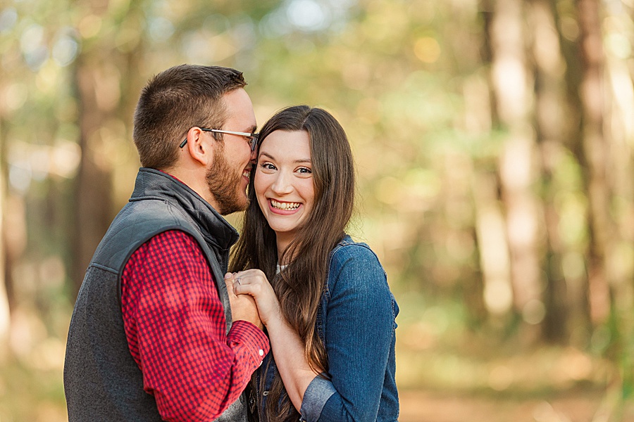 couple snuggling in red plaid in woods
