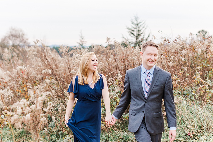 couple walking through tall grasses holding hands