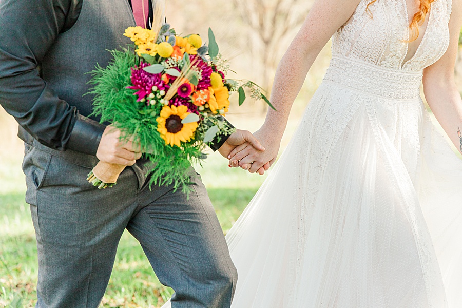 bride and groom holding hands with sunflower bouquet