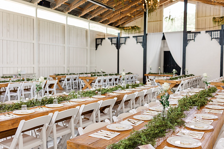 long banquet tables at indoor wedding with greenery