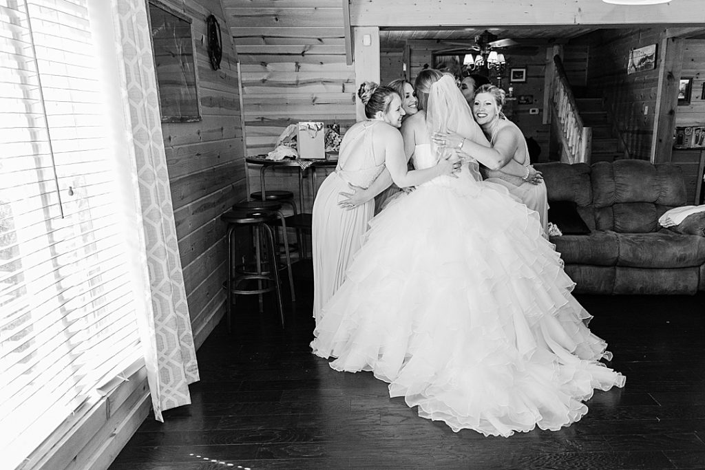 bridesmaids hugging bride on wedding day