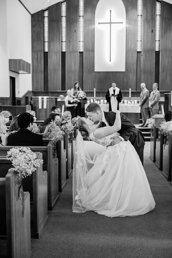 bride and groom dip kissing down the aisle