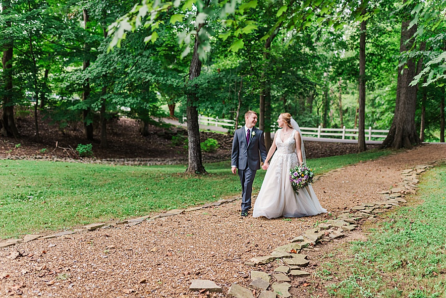 bride and groom walking down wooded path
