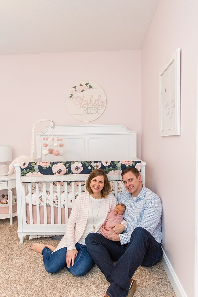 mom and dad with newborn in pink nursery