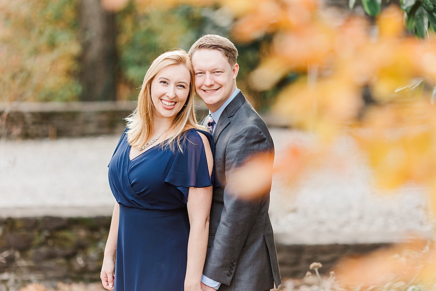couple smiling at camera with golden orange leaves