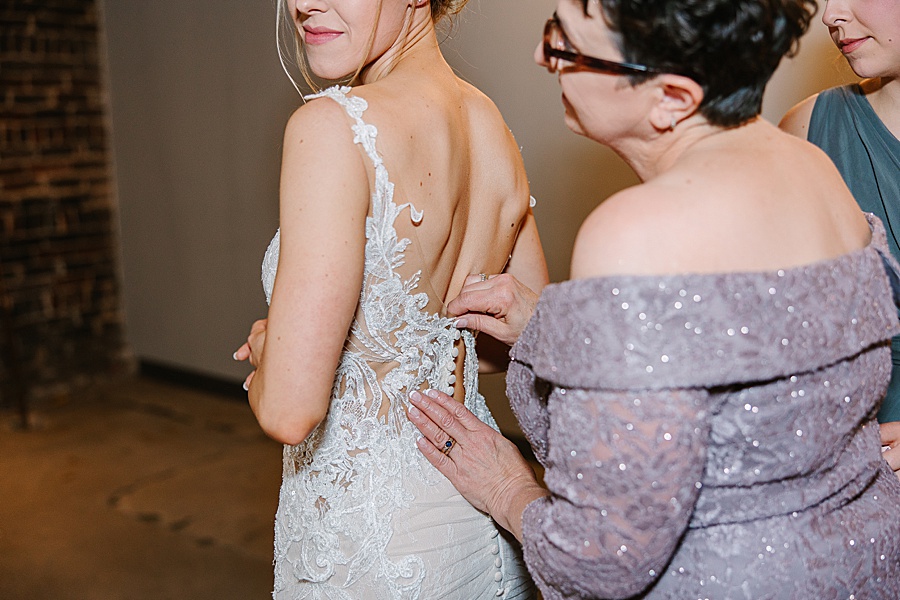 lace wedding dress with satin buttons being buttoned by mom at Jackson Terminal in Knoxville TN by Mandy Hart Photo, Knoxville TN Wedding Photographer