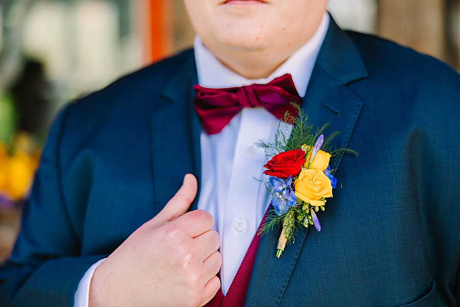 boutonniere with red and yellow roses on navy suit at boutonniere