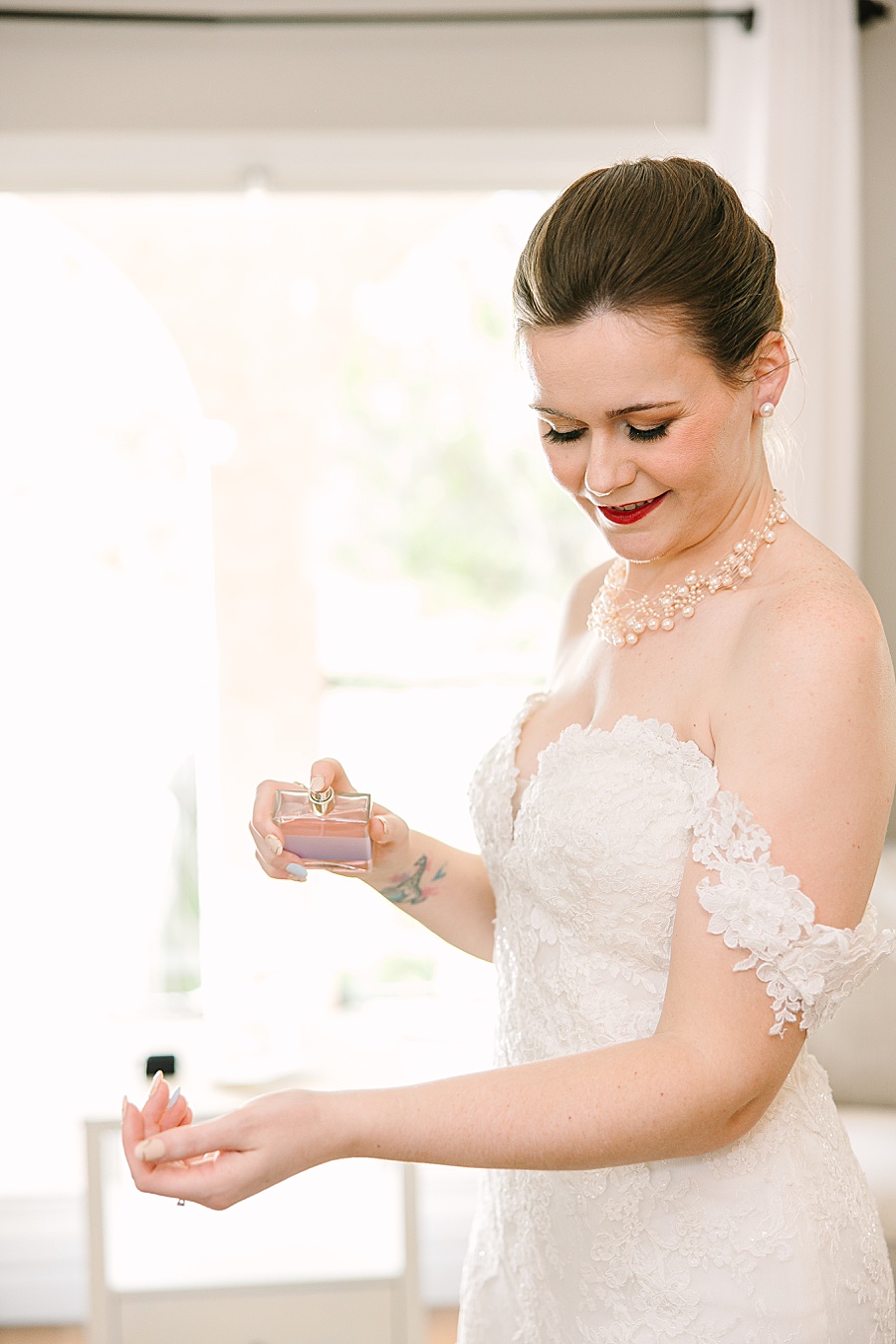 bride putting on perfume on wedding day