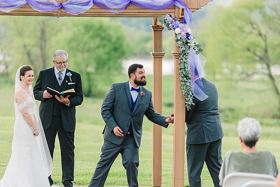 groom getting rings from best man during wedding ceremony