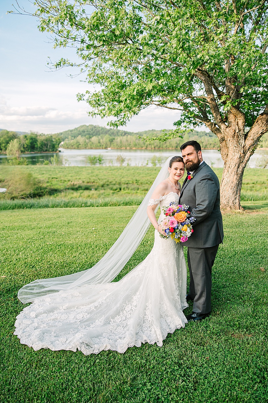 Bride and groom portrait with tree in front of river at Tennessee Riverplace in Chattanooga