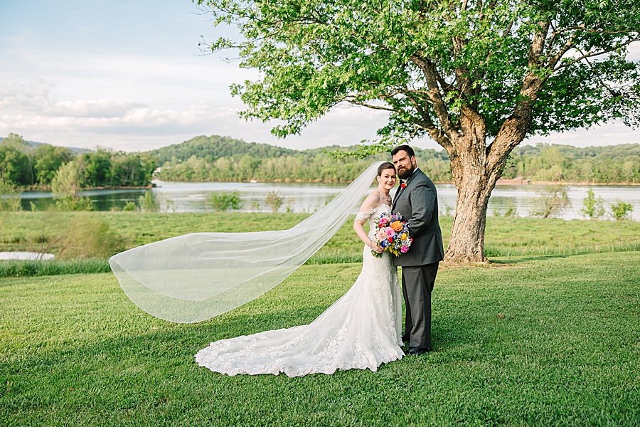 Bride and groom portrait with flying veil in front of river at Tennessee Riverplace in Chattanooga