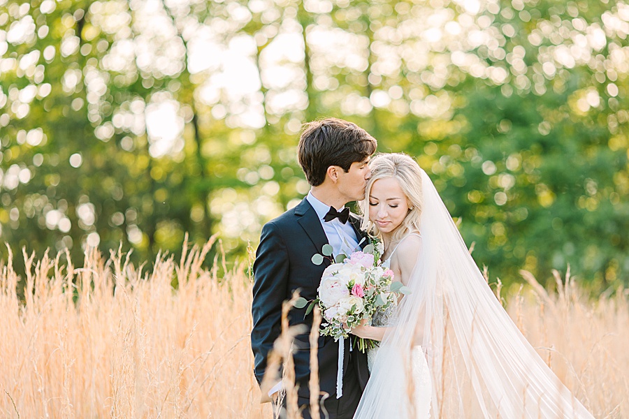 bride and groom kissing during golden hour in a field of rye grass