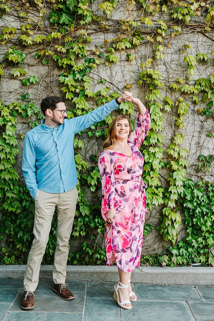 couple twirling in front of an ivy covered wall in the bluff view arts district