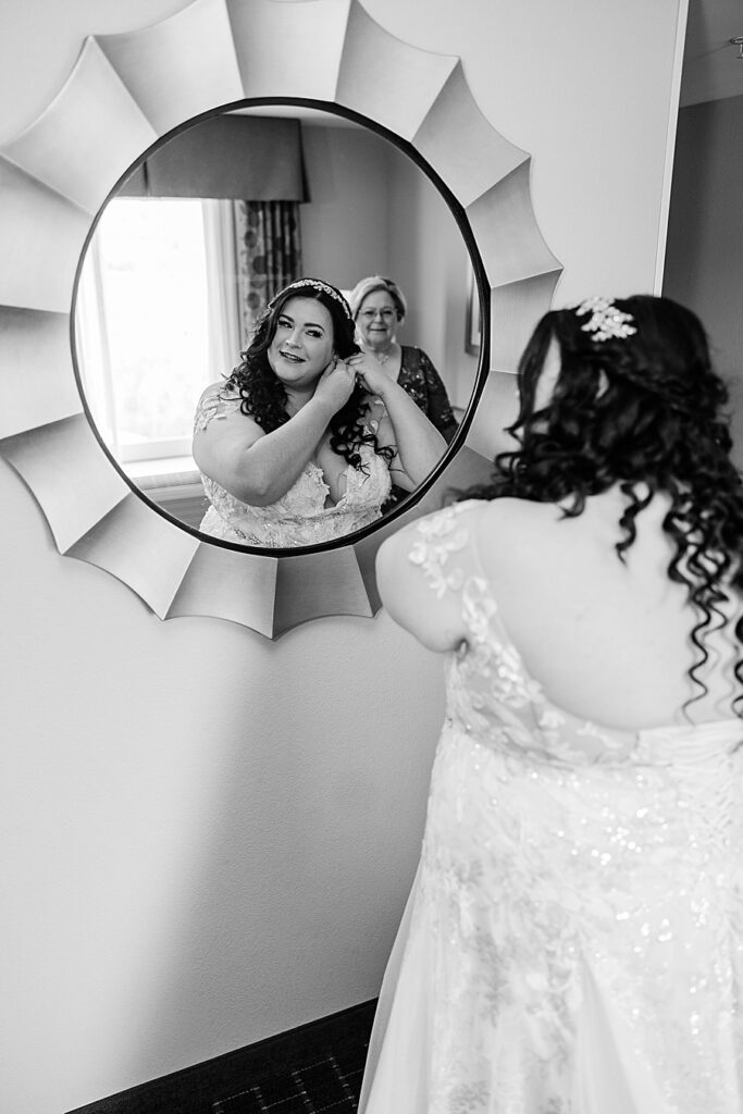 bride looking in mirror putting on earrings