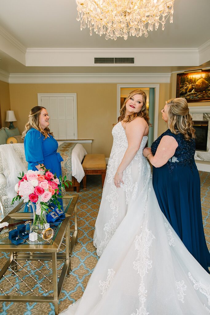 Mom and sister helping bride get dress for wedding