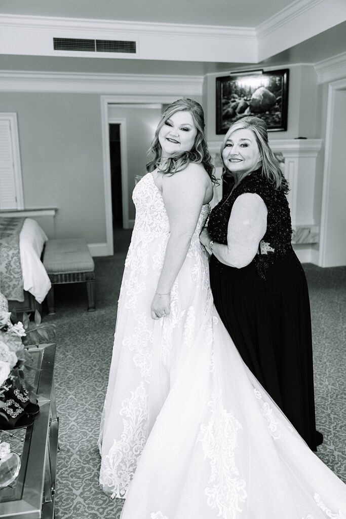 mom helping daughter get dressed on wedding day