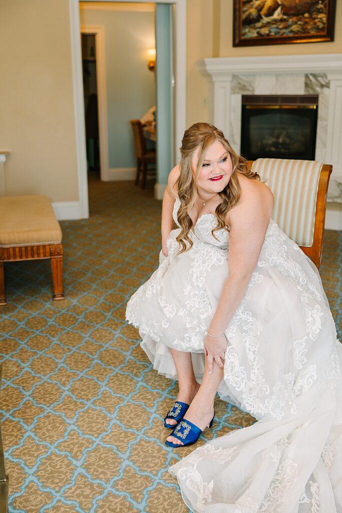 Bride putting on blue satin manolo blahnik wedding shoes