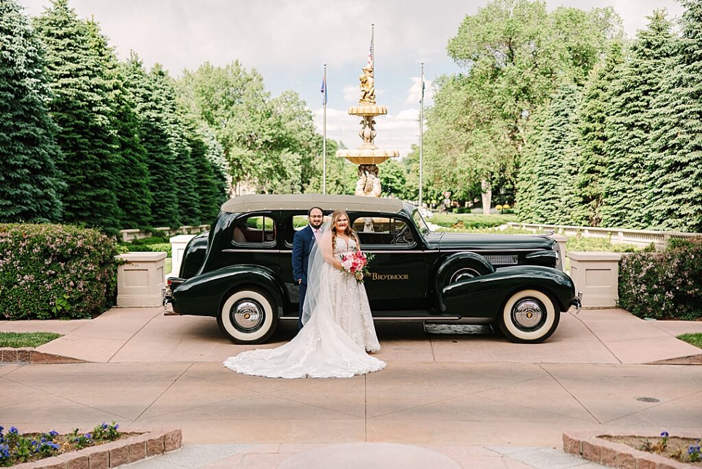 bride and groom in front of black classic car at the broadmoor resort in Colorado Springs on wedding day