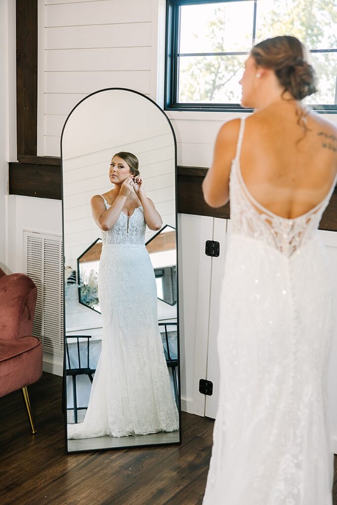 bride looking in the mirror putting on her earrings