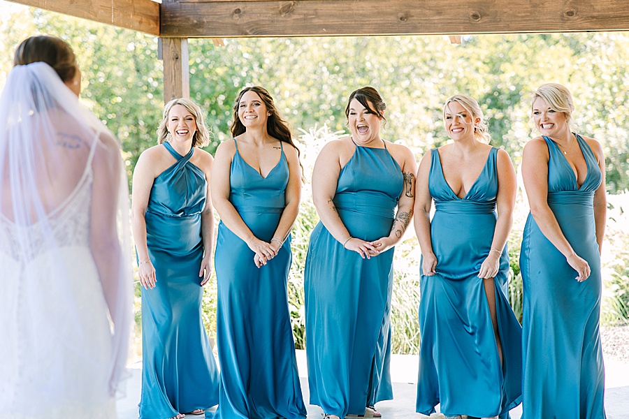 bridesmaids in blue satin dresses looking at bride