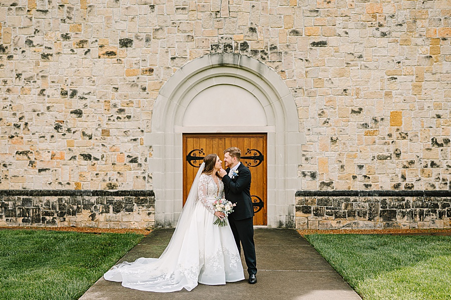 bride and groom kissing outside of catholic church