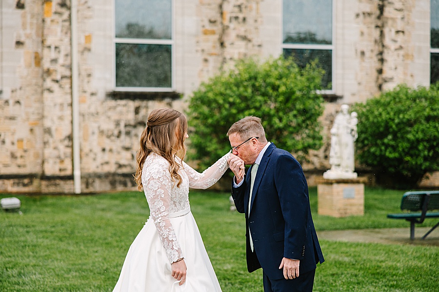 dad kissing daughter's hand before her wedding ceremony