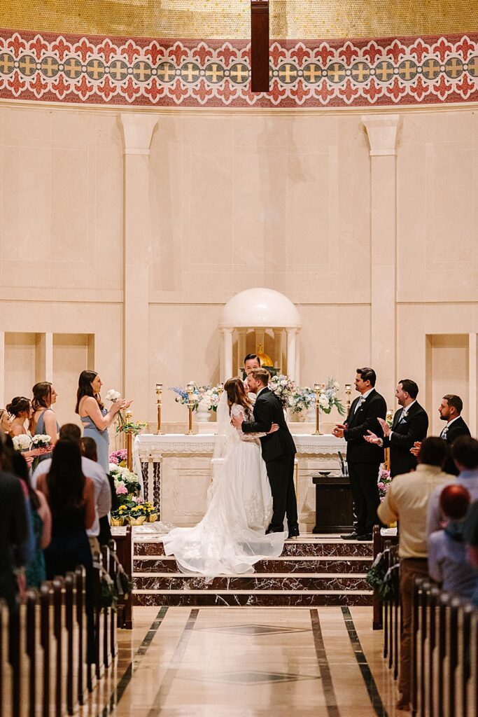 bride and groom first kiss during catholic wedding ceremony