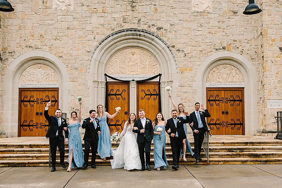 wedding party cheering outside of catholic church after wedding