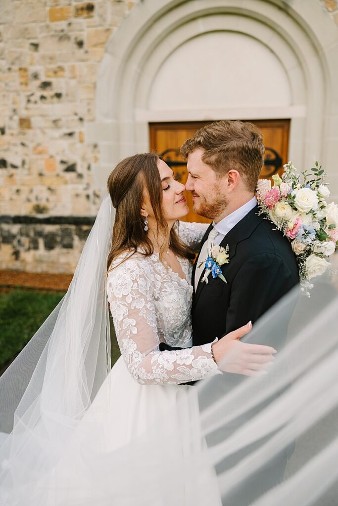 bride and groom embracing with a swooping veil in the foreground