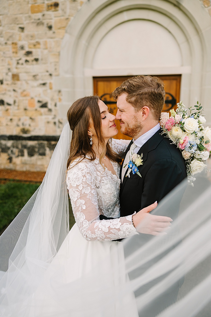 bride and groom embracing with a swooping veil in the foreground