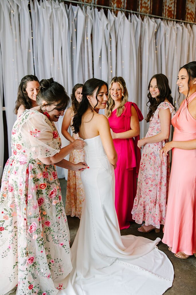 mom zipping up bride's wedding gown while getting ready on wedding day at the venue at the bluffs