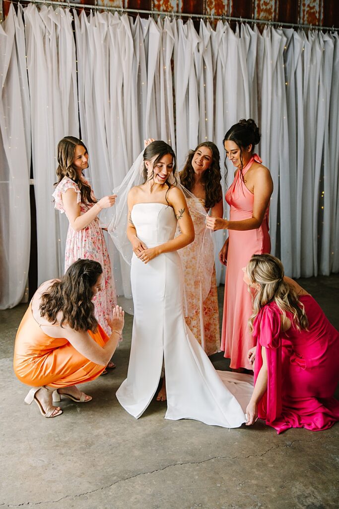 bridesmaids fluffing and helping bride getting dressed on wedding day at venue at the bluffs
