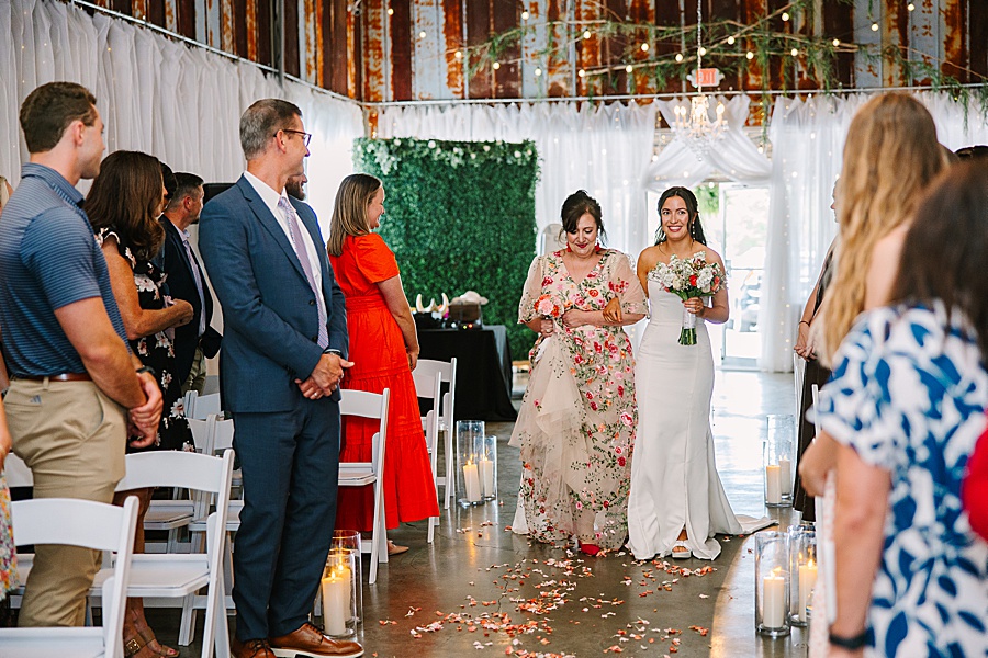 bride being walked down the aisle by her mother on her wedding day venue at the bluffs