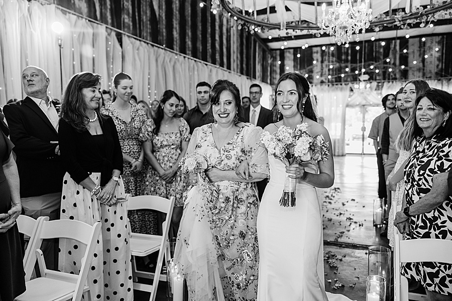 bride being walked down the aisle by her mother on her wedding day venue at the bluffs