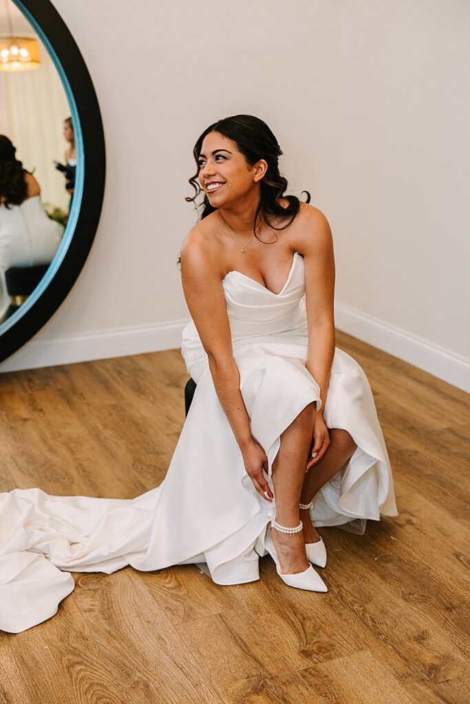 Bride smiling at bridesmaids while putting on her wedding shoes at Nichols Heir in Sevierville TN