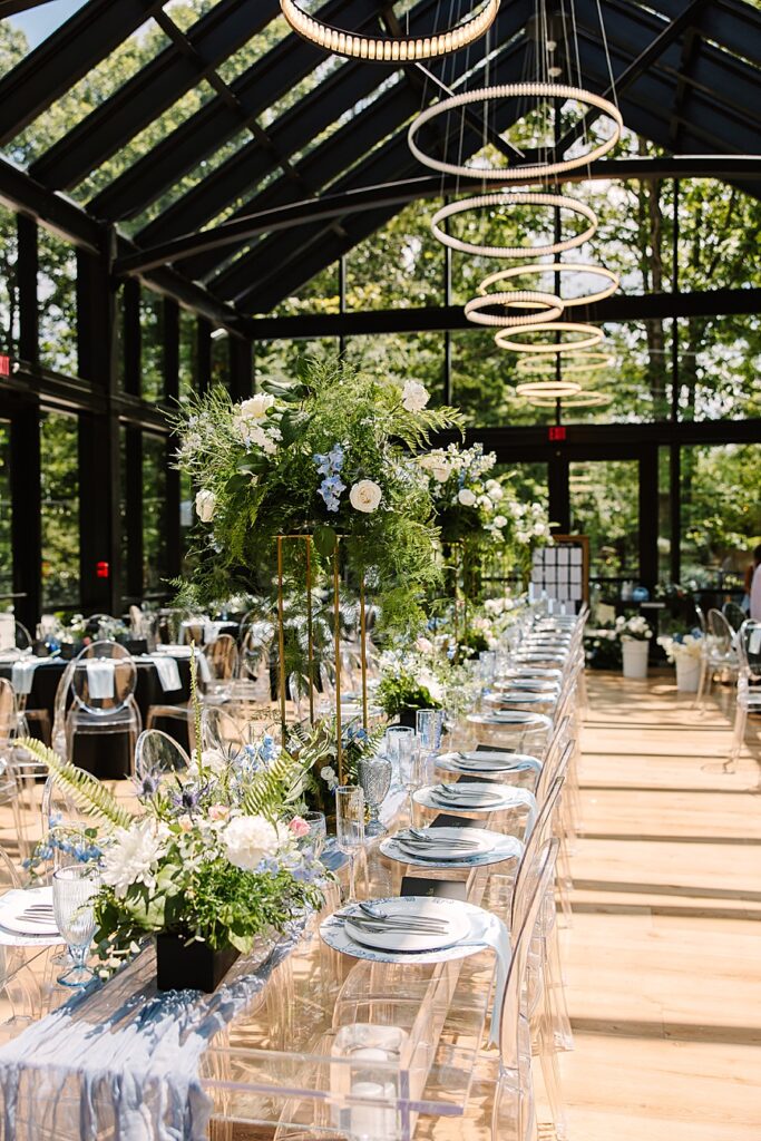 interior detail photos of the glass house reception site at Nichols Heir with lush floral arrangements and lucite tables and chairs