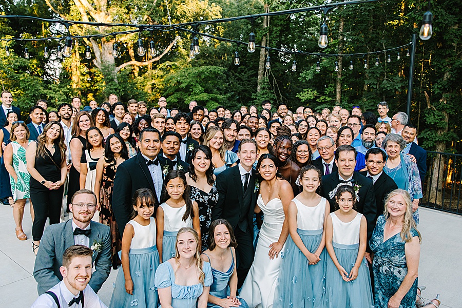 group photo of guests on patio at Glass House at Nichols Heir under twinkling bistro lights