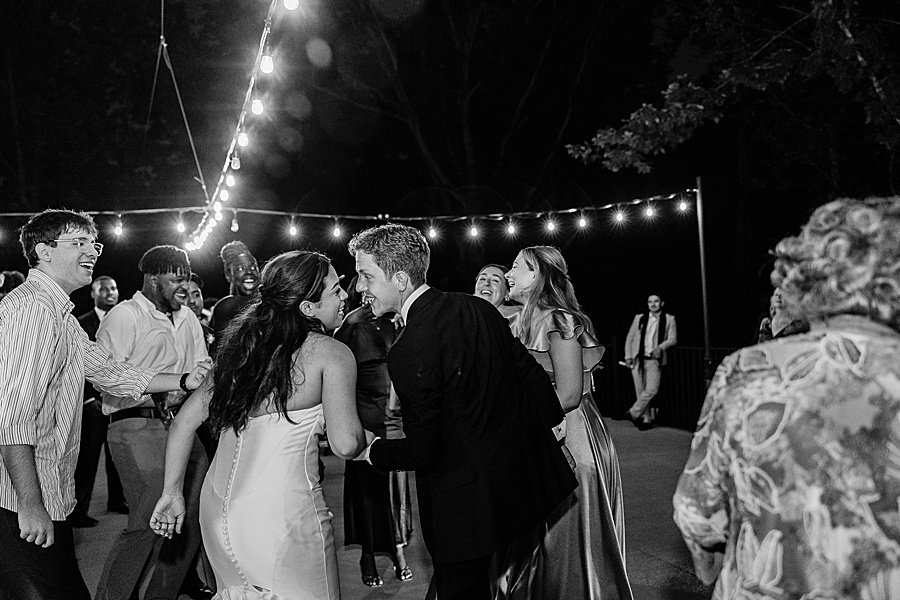 bride and groom dancing under sparkling bistro lights on patio at glass house at Nichols Heir
